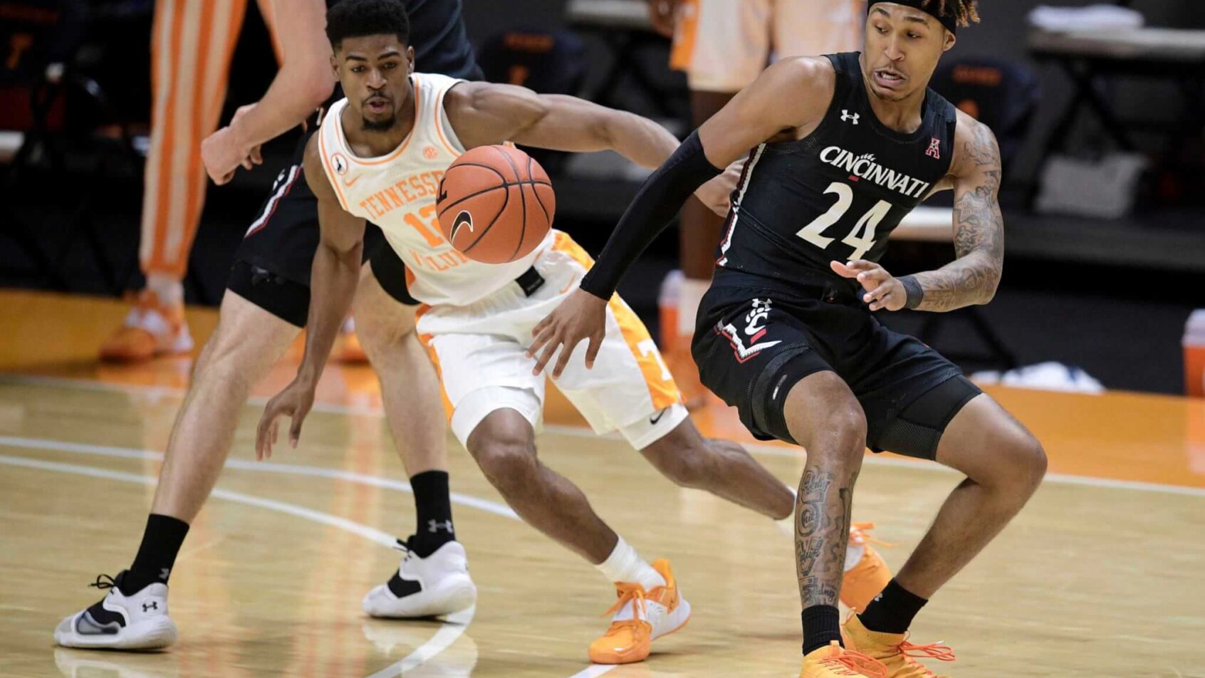 Cincinnati men's basketball guard Jeremiah Davenport losing control of the ball during a game. Tennessee guard Victor Bailey Jr. is attempting to gain possession of it..
