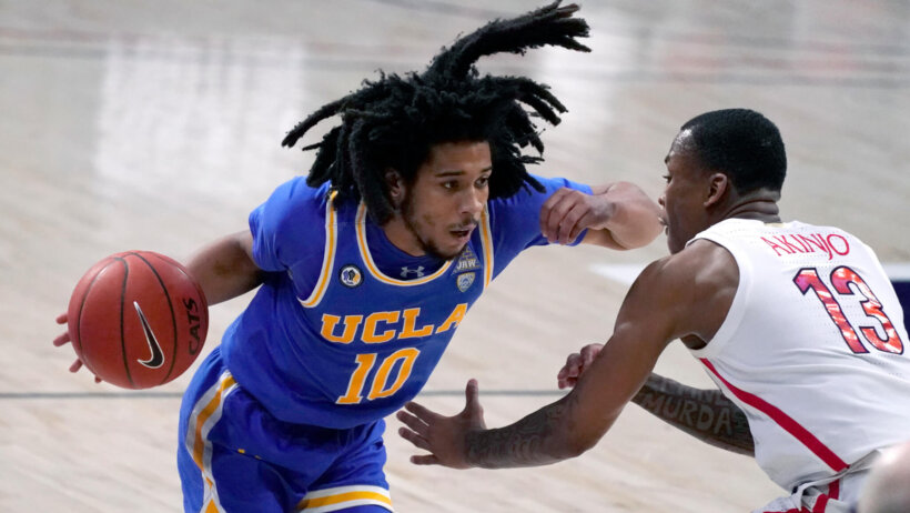 UCLA guard Tyger Campbell driving on Arizona guard James Akinjo during a game.