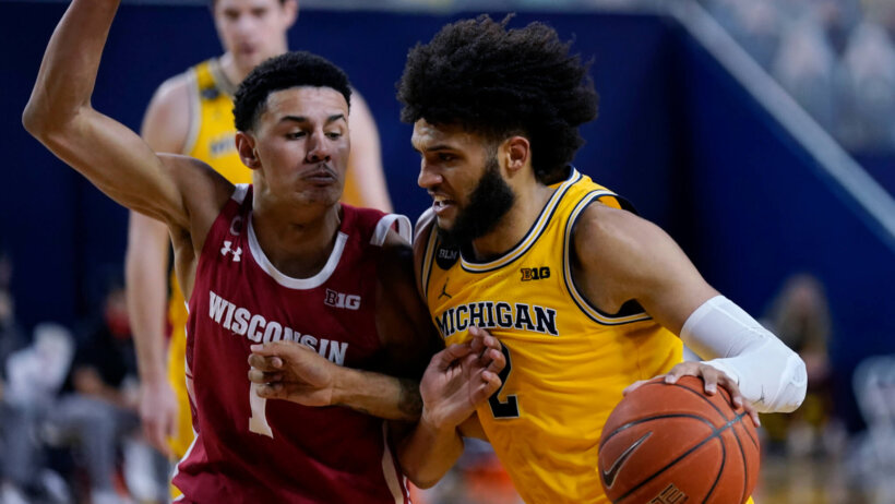 Michigan forward Isaiah Livers driving to the net against Wisconsin guard Jonathan Davis during a NCAA men's basketball game.