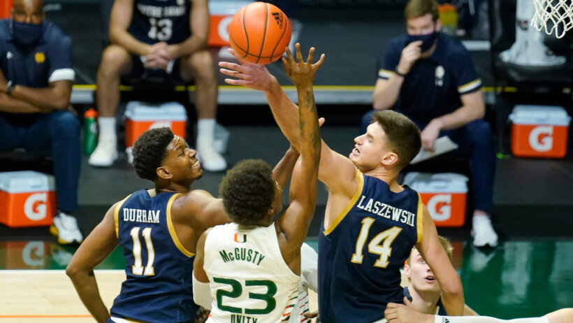 Notre Dame forward Nate Laszewski blocking a shot by Miami guard Kameron McGusty during a NCAA basketball game.