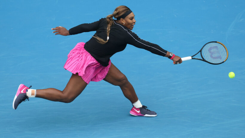 Serena Williams stretching to make a backhand return in a match.