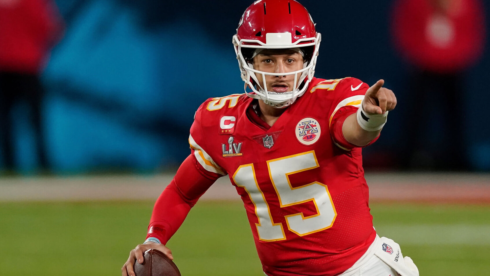 Patrick Mahomes pointing while on the run with football in right hand