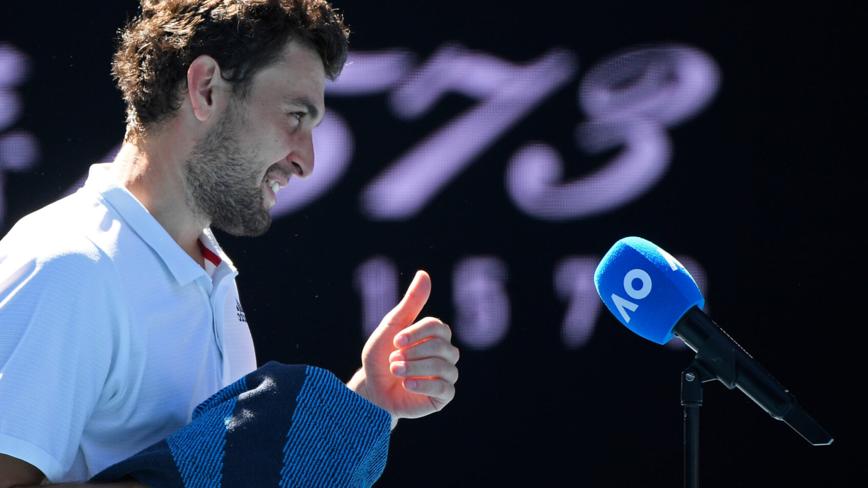 Aslan Karatsev being interviewed after a win during the Australian Open. He is giving a thumbs up and smiling.