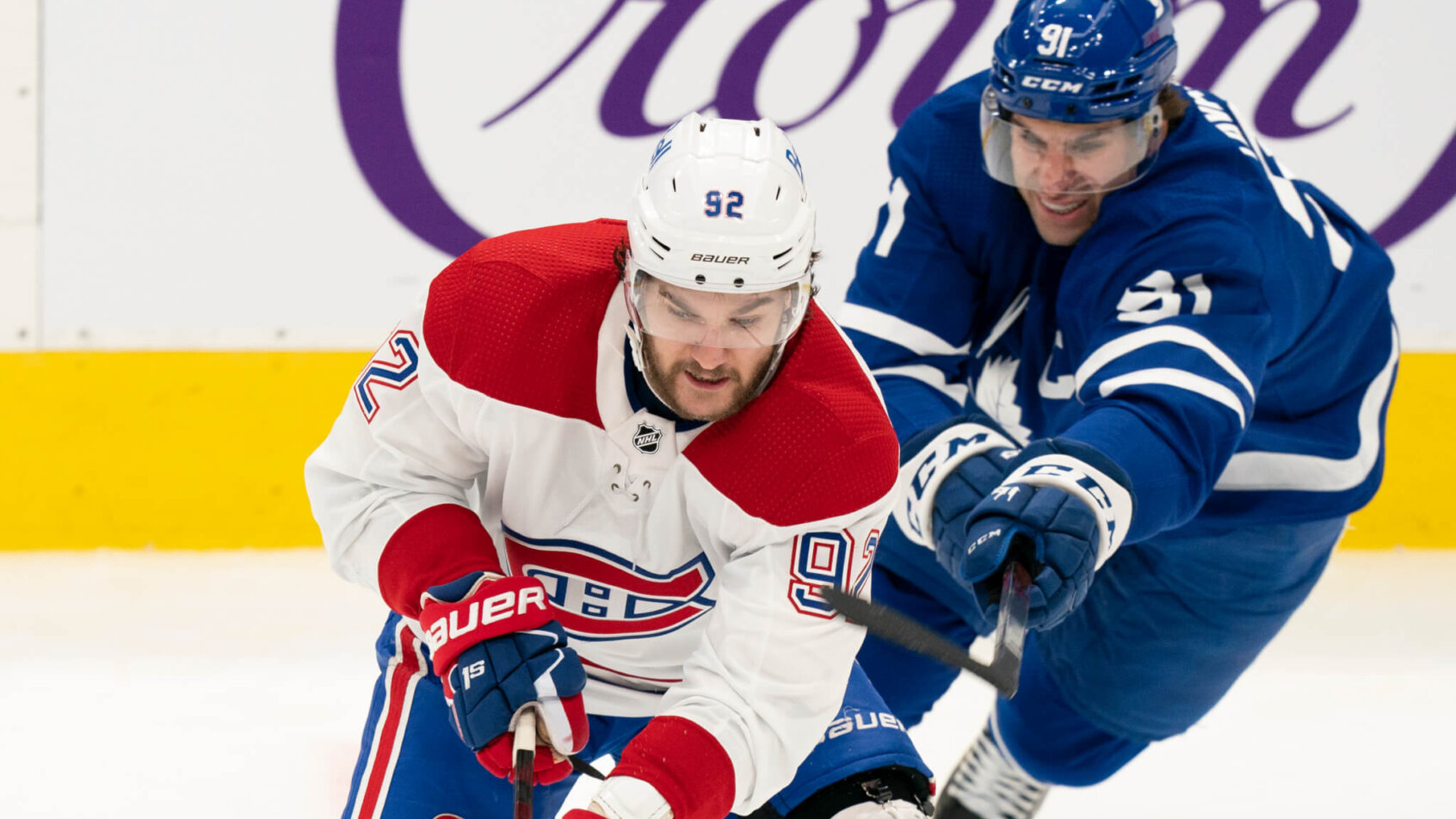 Toronto Maple Leafs center John Tavares attempting to hook Montreal Canadians left winger Jonathan Drouin during an NHL game.
