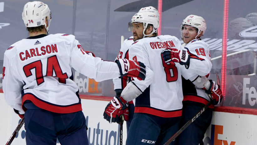 Washington Capitals' Nicklas Backstrom celebrating with teammates on the ice after scoring a goal during a NHL game.
