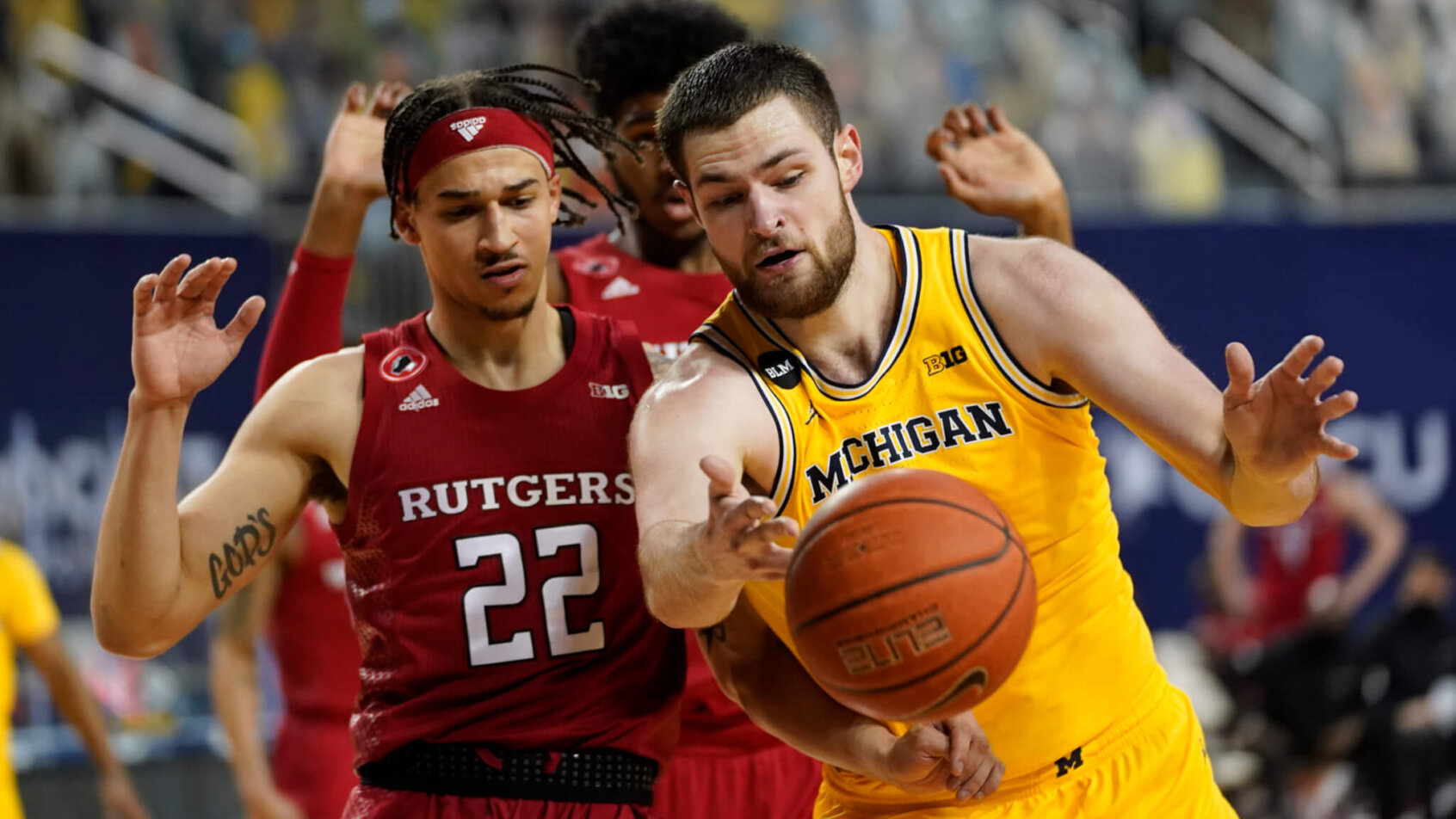 Rutgers guard Caleb McConnell and Michigan Wolverines center Hunter Dickinson battling for a loose ball during a NCAA men's basketball game.