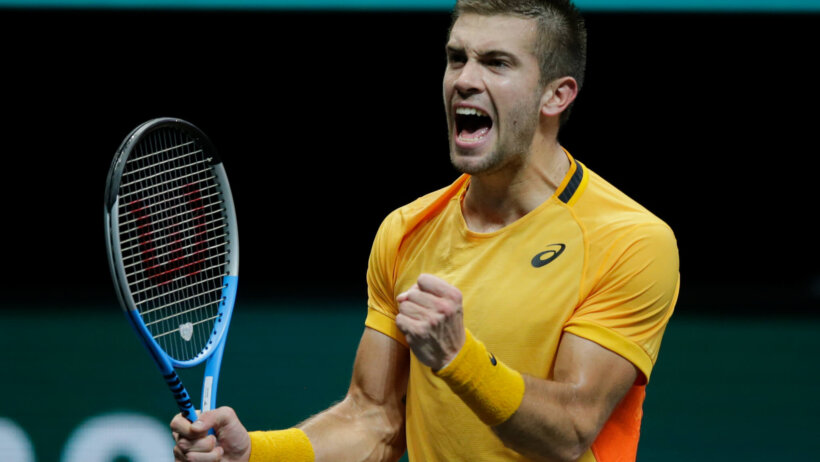 Borna Coric celebrating a win on the court by pumping his fist.