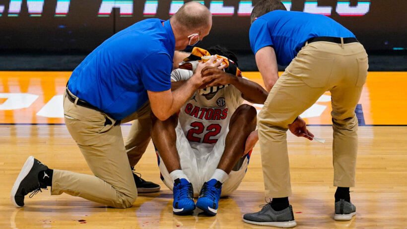 Two trainers tend to Tyree Appleby, holding a towel to his forehead.