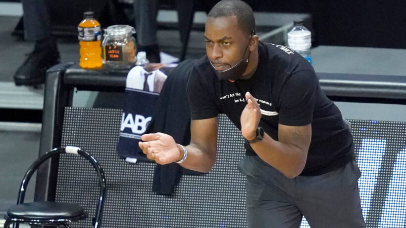 Oklahoma State head coach Mike Boynton clapping on his team from the sidelines during a NCAA college tournament basketball game.
