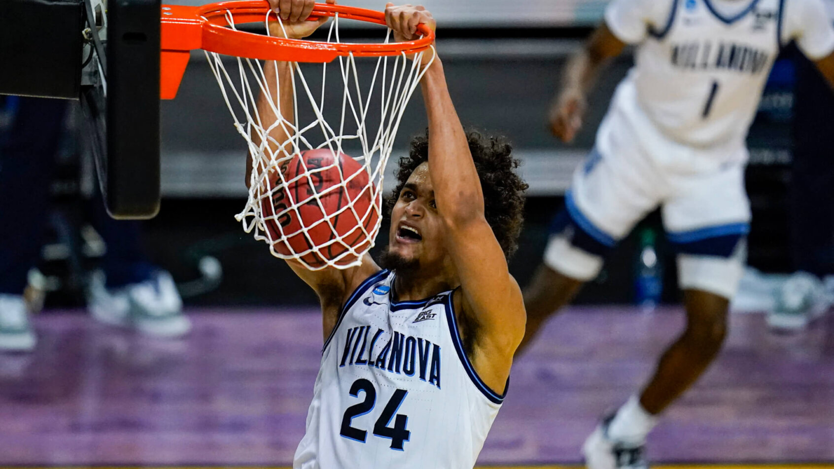 Villanova forward Jeremiah Robinson-Earl hanging from the basket after a dunk during a NCAA men's basketball game.