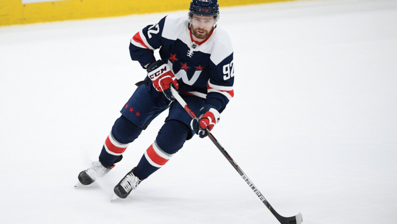 Washington Capitals player Evgeny Kuznetsov skating on the ice with the puck during an NHL game.