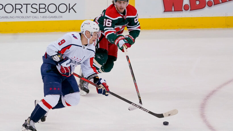 New Jersey Devils center Jack Hughes playing defense against the Washington Capitals during a NHL game.