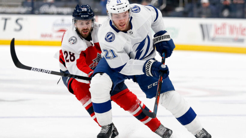Tampa Bay Lightning forward Brayden Point chasing the puck in from of Blue Jackets forward Oliver Bjorkstrand on the ice during a game.