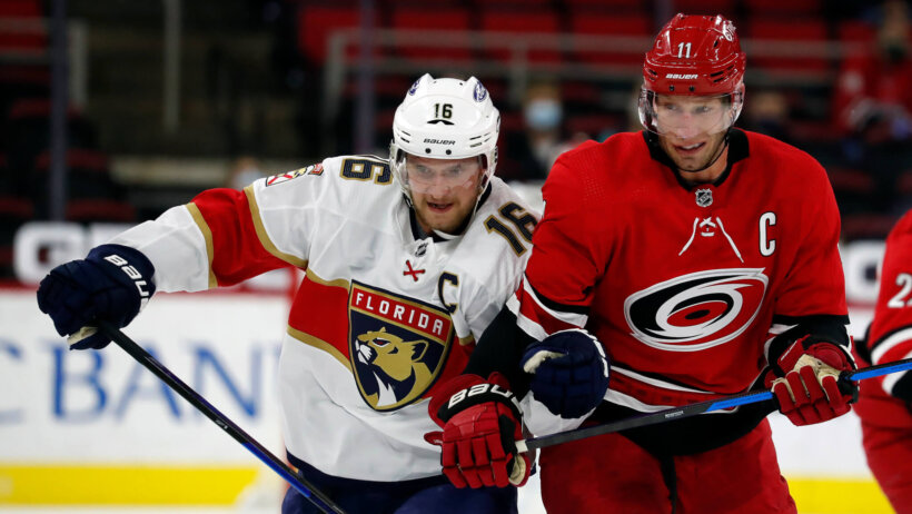 Florida Panthers' Aleksander Barkov battles on the ice for the puck against Carolina Hurricanes' Jordan Staal during an NHL game.