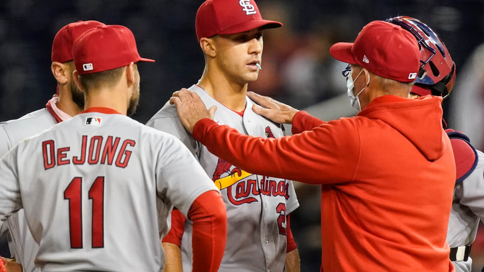 Coach with hands on shoulder of Jack Flaherty, with teammates surrounding them