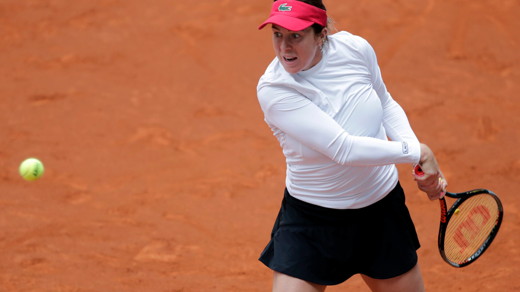 Anastasia Paulyuchenkova hitting a backhand return during a clay court tennis match.