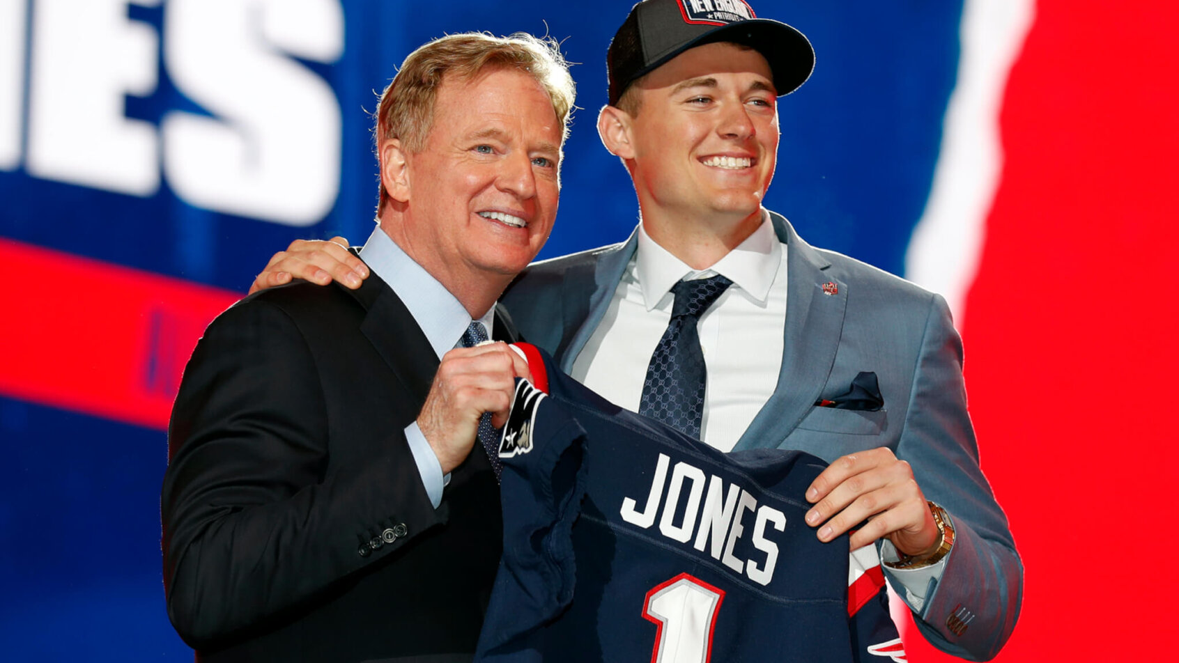Alabama quarterback Mac Jones holding a team jersey with NFL Commissioner Roger Goodell after New England Patriots selected him in the draft.