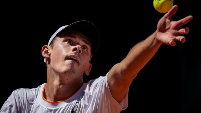 Alex de Minaur serving the ball during a tennis match.