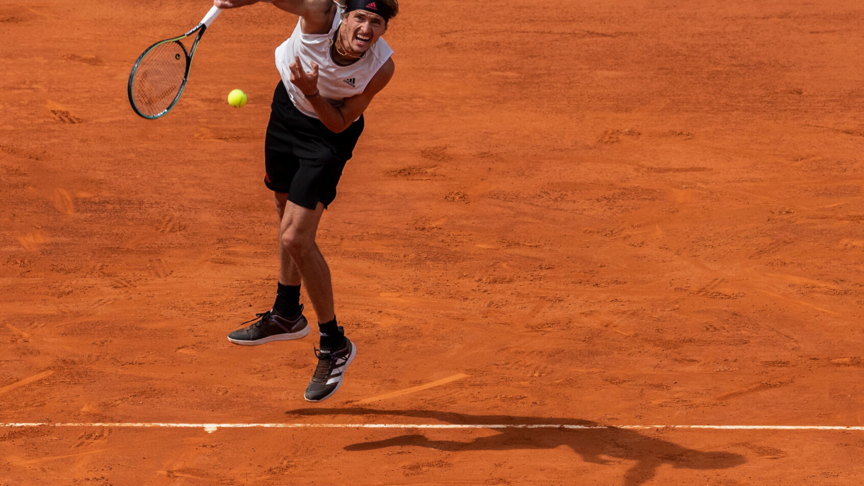 Alexander Zverev serving during a tennis match on clay court.