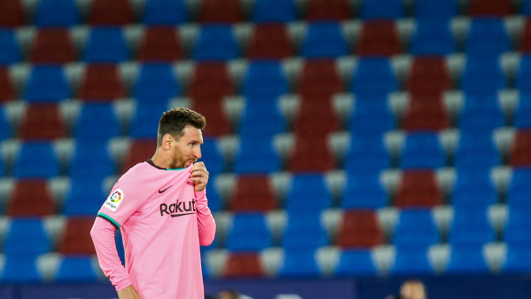 Lionel Messi reacting with his shirt over his mouth on the soccer field during a match.