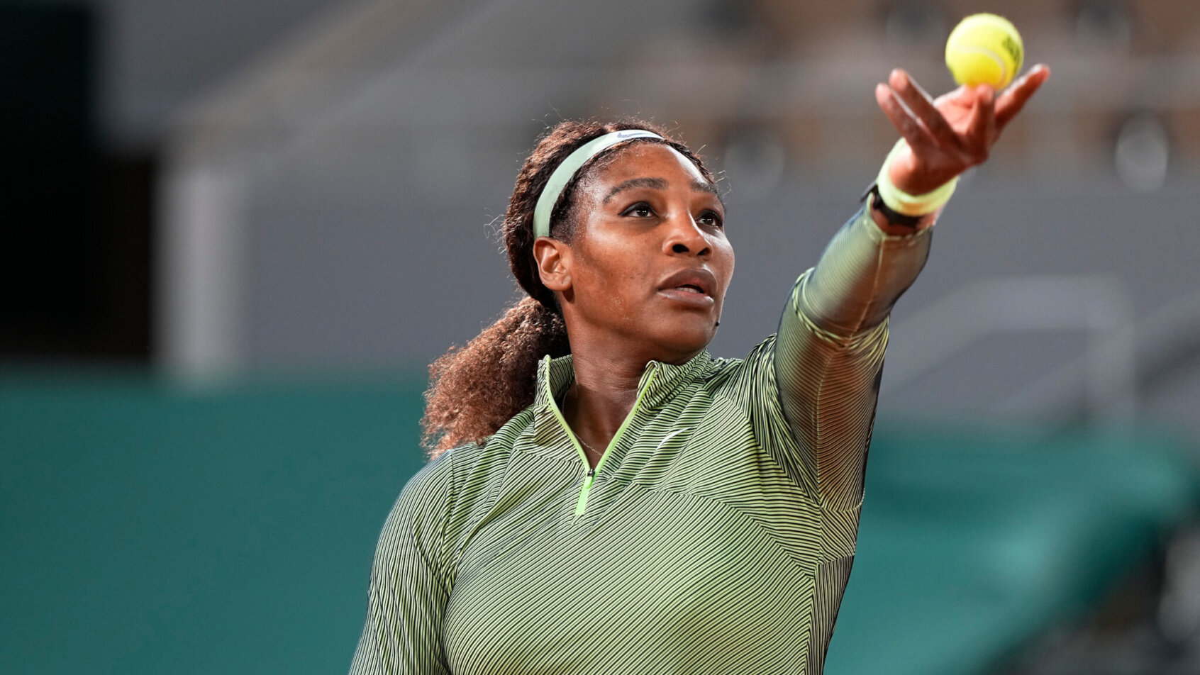 Serena Williams throwing the ball up to hit a serve during a match at the 2021 French Open.