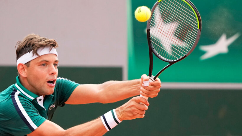 Filip Krajinovic hitting a return during a tennis match.