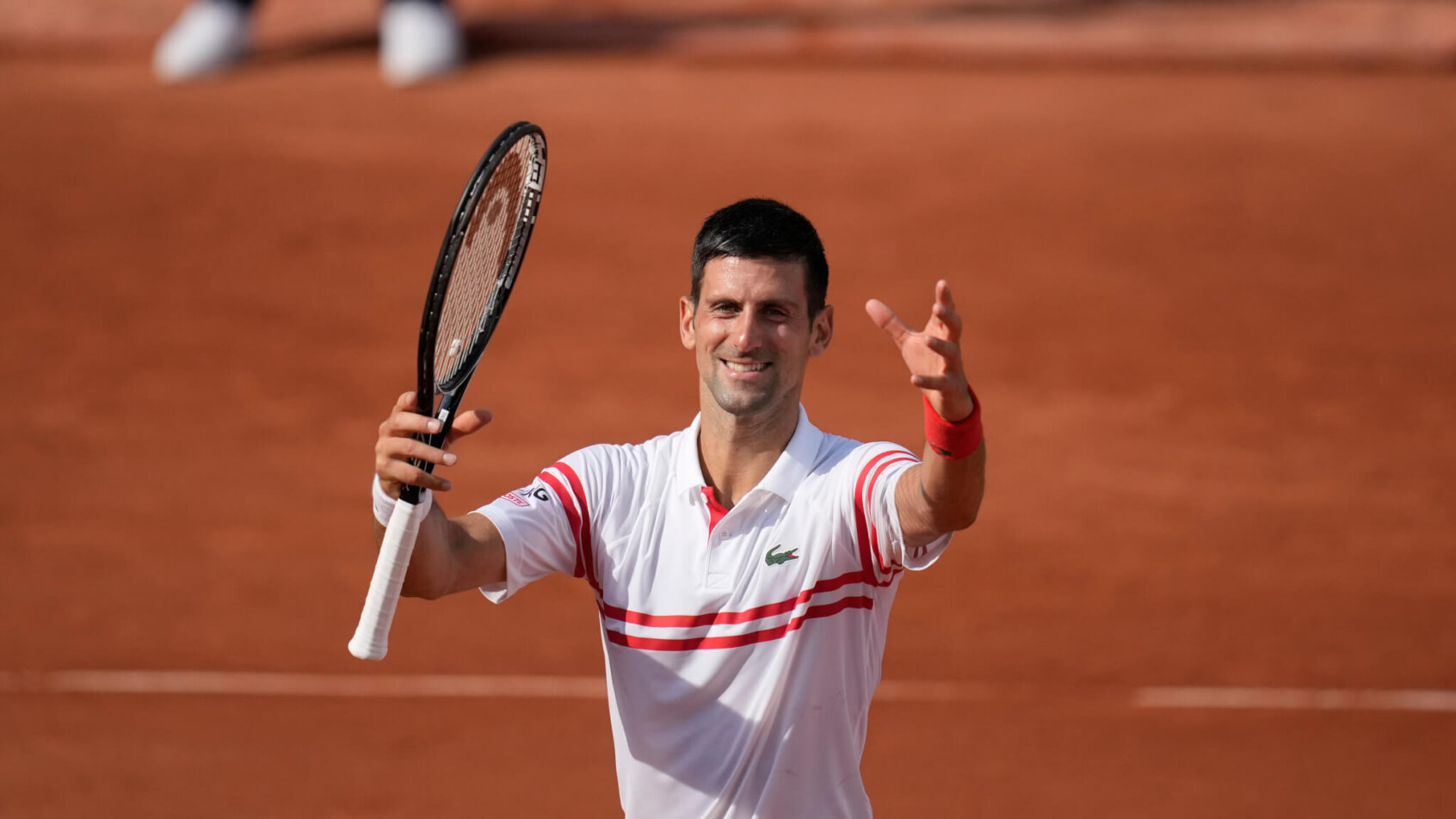Novak Djokovic celebrating on the court after winning a match at the 2021 French Open.