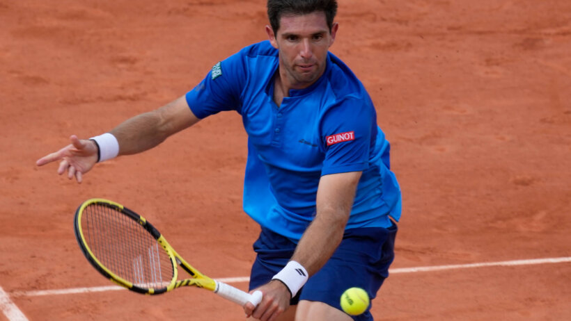 Federico Delbonis hitting a return during a tennis match on clay.