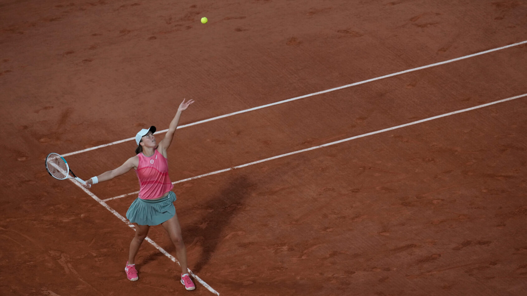 A wide shot of Iga Swiatek serving during a match at the 2021 French Open.