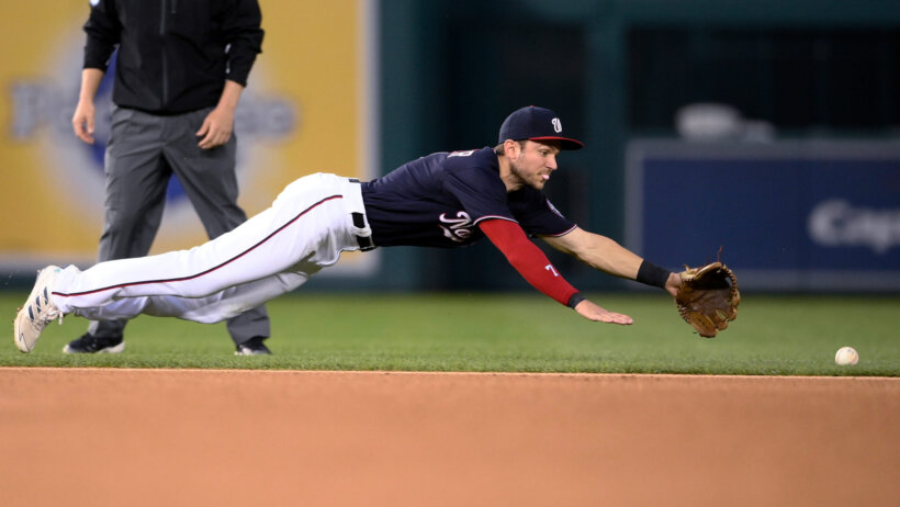 Shortstop Trea Turner diving for a ball during a MLB game.