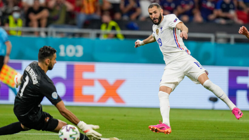 France's Karim Benzema kicking the ball past Portugal's goalkeeper to score during a soccer match.