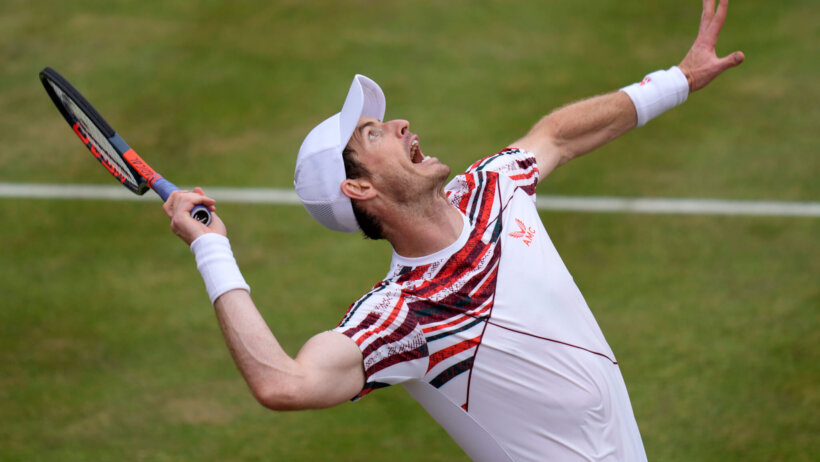 Andy Murray serving during a tennis match on grass.