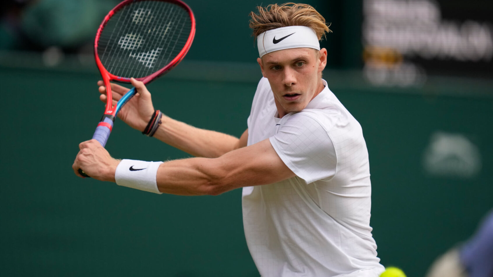 Denis Shapovalov hitting a return during a tennis match at Wimbledon.