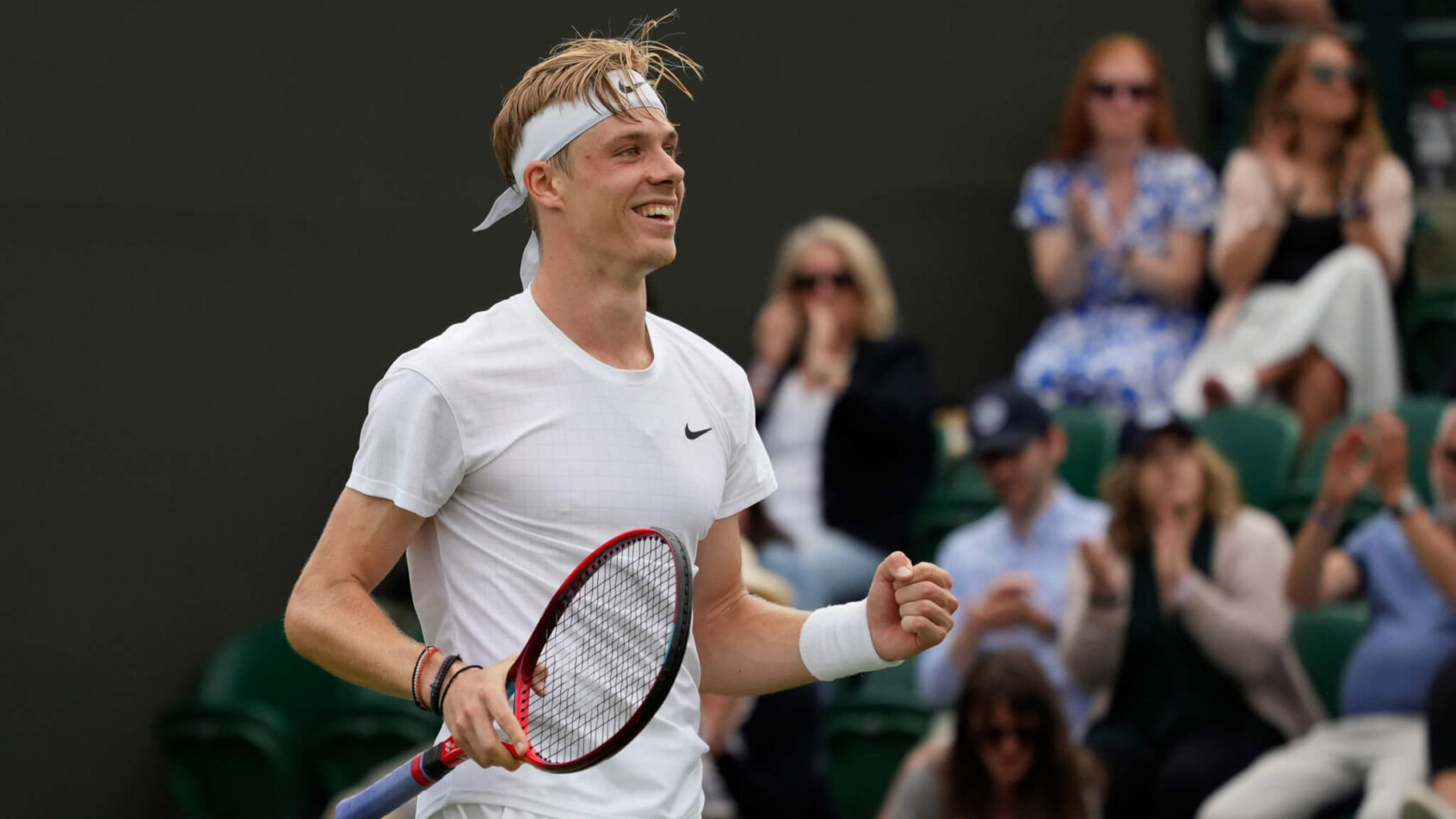 Denis Shapovalov celebrating with a first pump and smile after winning a match at Wimbledon.