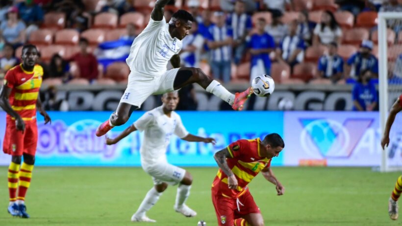 Honduras player leaping in air to control soccer ball with left foot in front of defender
