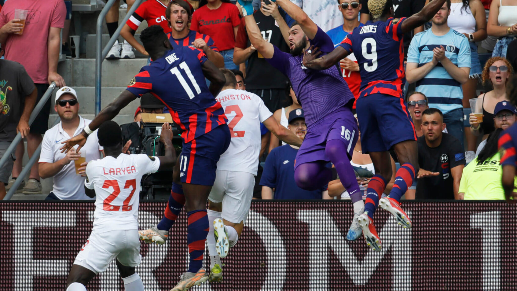 Maxime Crepeau of Canada, leaping to grab a corner kick goal attempt from the United States players.