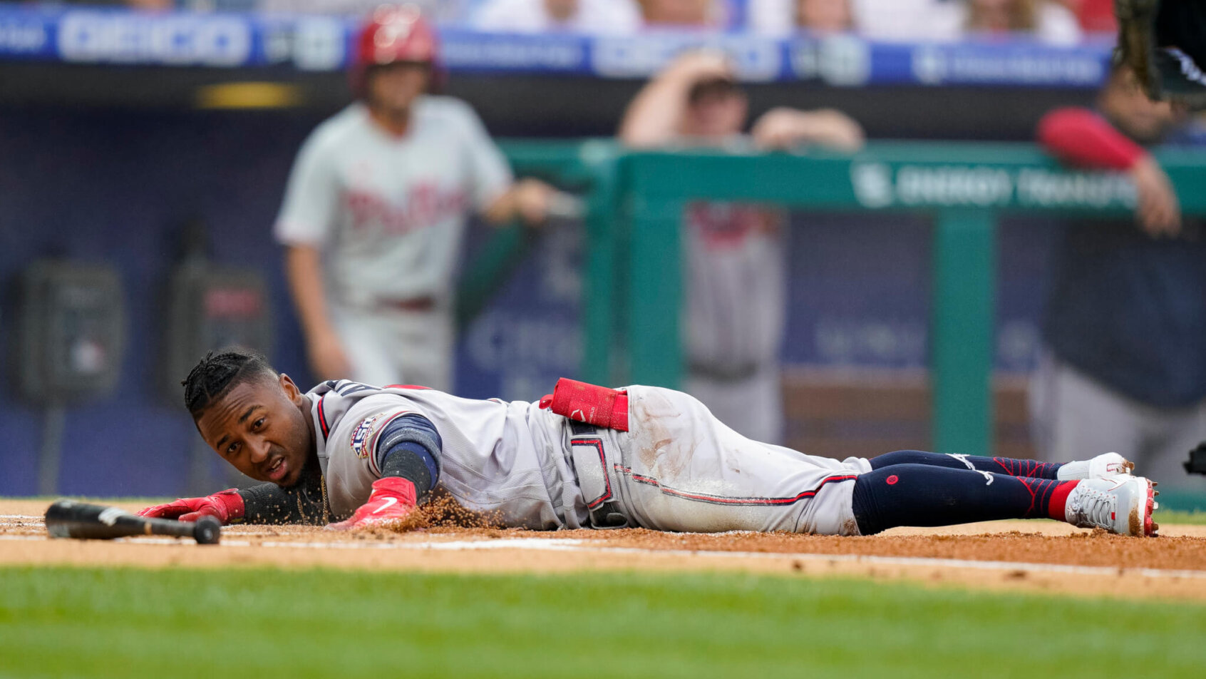 Atlanta Braves' Ozzie Albies stretched out on the ground over home plate after scoring a run during a baseball game.