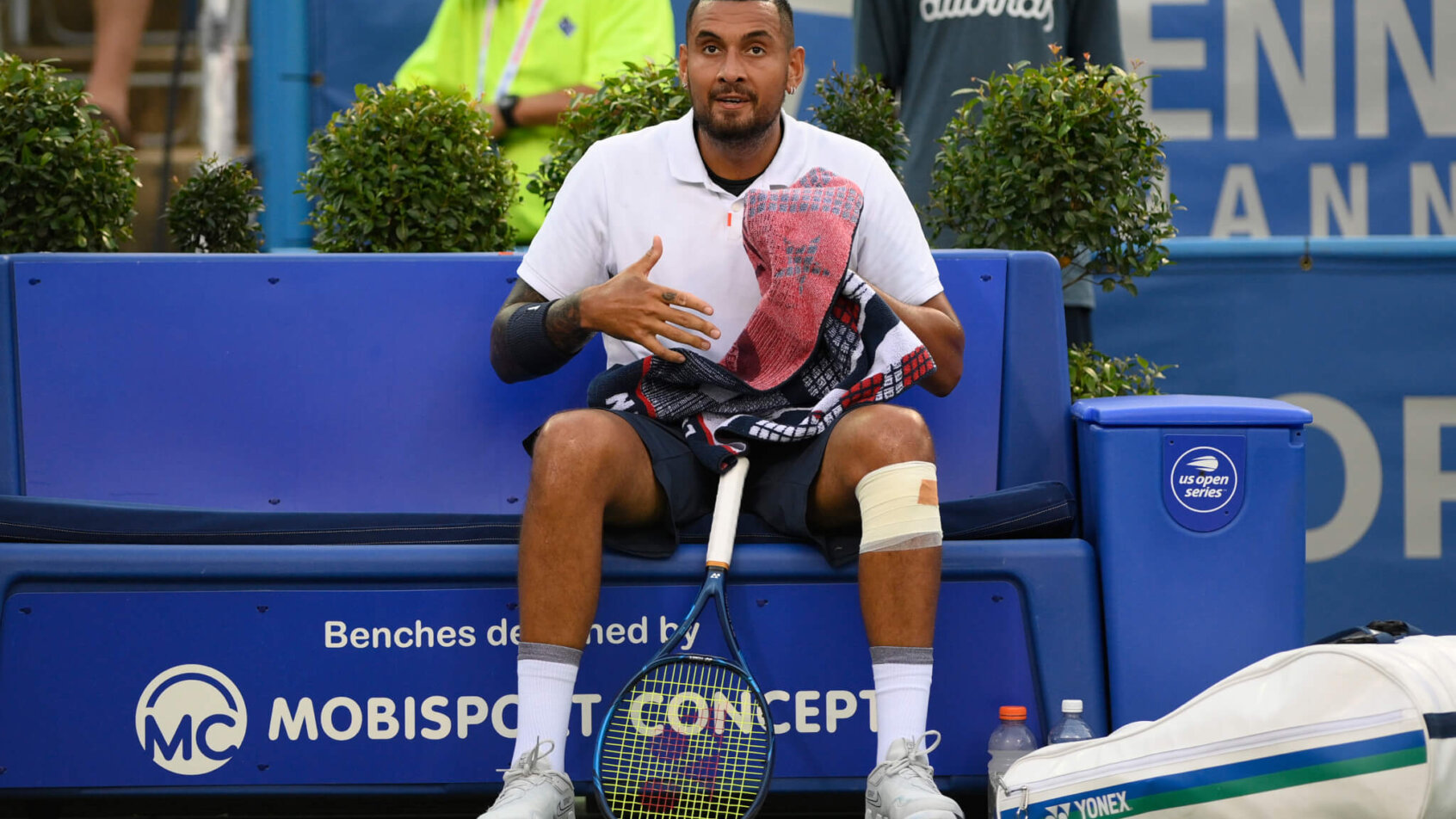 Nick Kyrgios resting during a break in a tennis match.