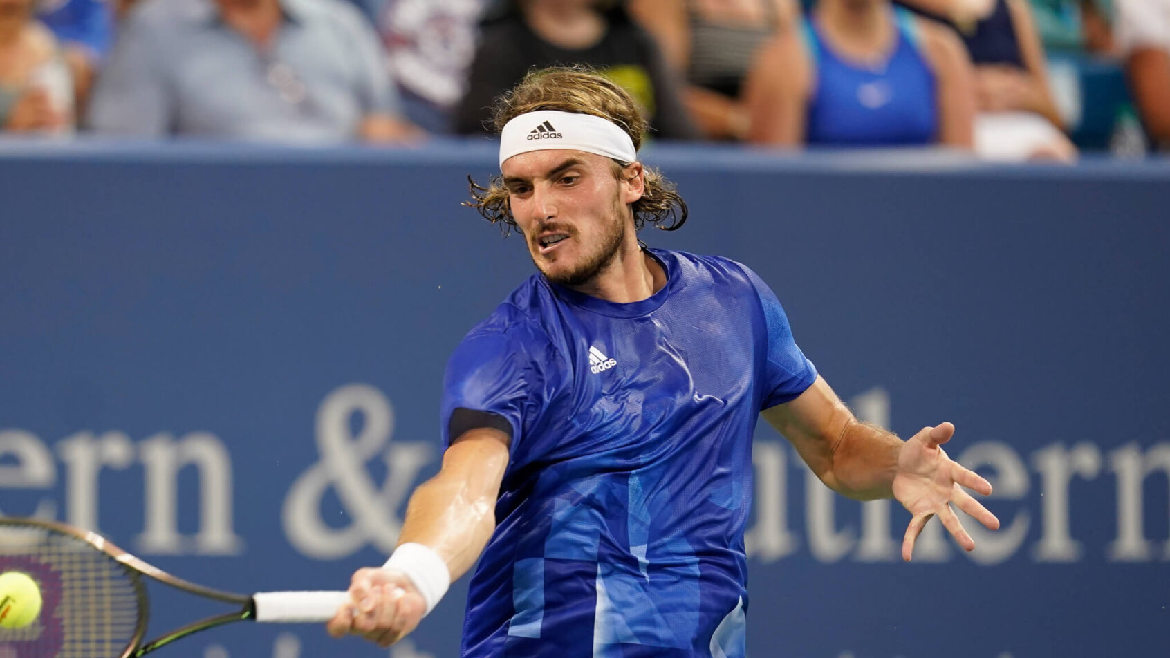 Stefanos Tsitsipas returning a shot during a tennis match.