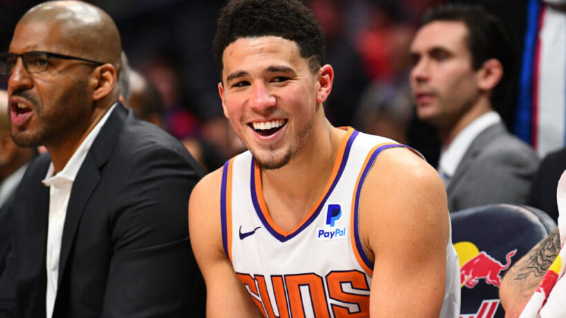 Devin Booker smiling on bench