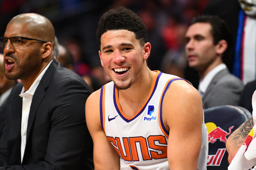 Devin Booker smiling on bench