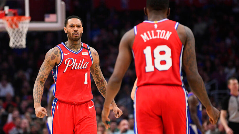 Philadelphia 76ers players Mike Scott and Shake Milton walking towards each other celebrating during a NBA game.