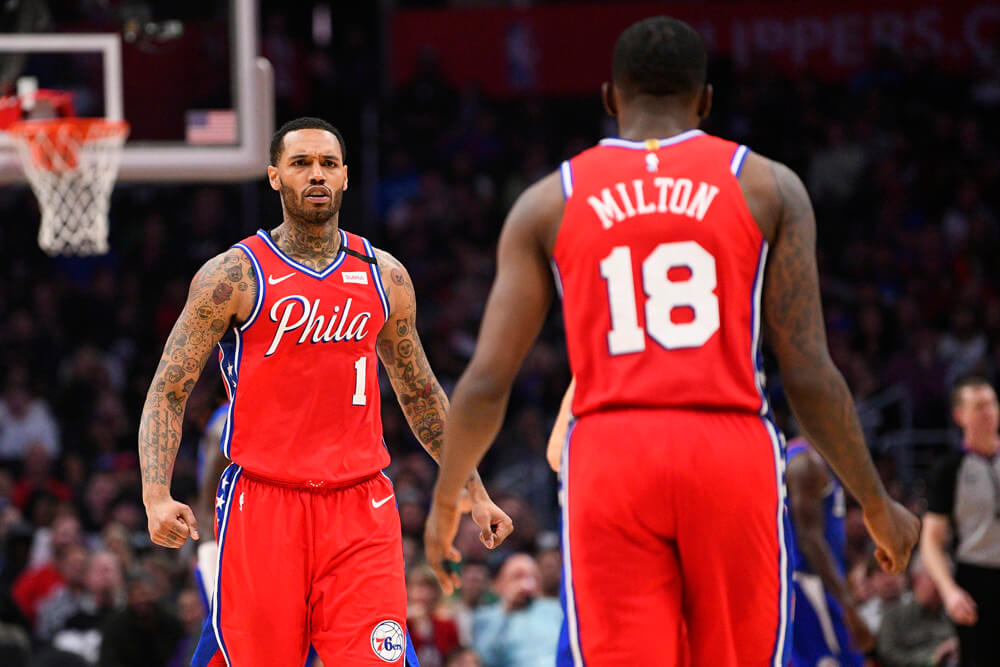 Philadelphia 76ers players Mike Scott and Shake Milton walking towards each other celebrating during a NBA game.