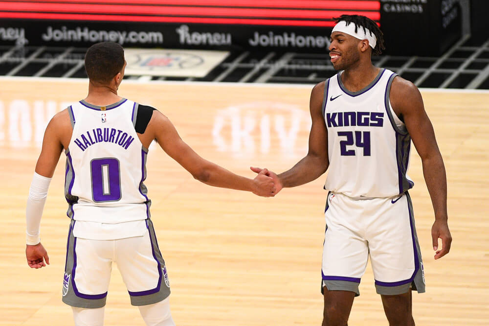 Sacramento Kings players Tyrese Haliburton and Buddy Hield high fiving in celebration during a NBA game on the court.