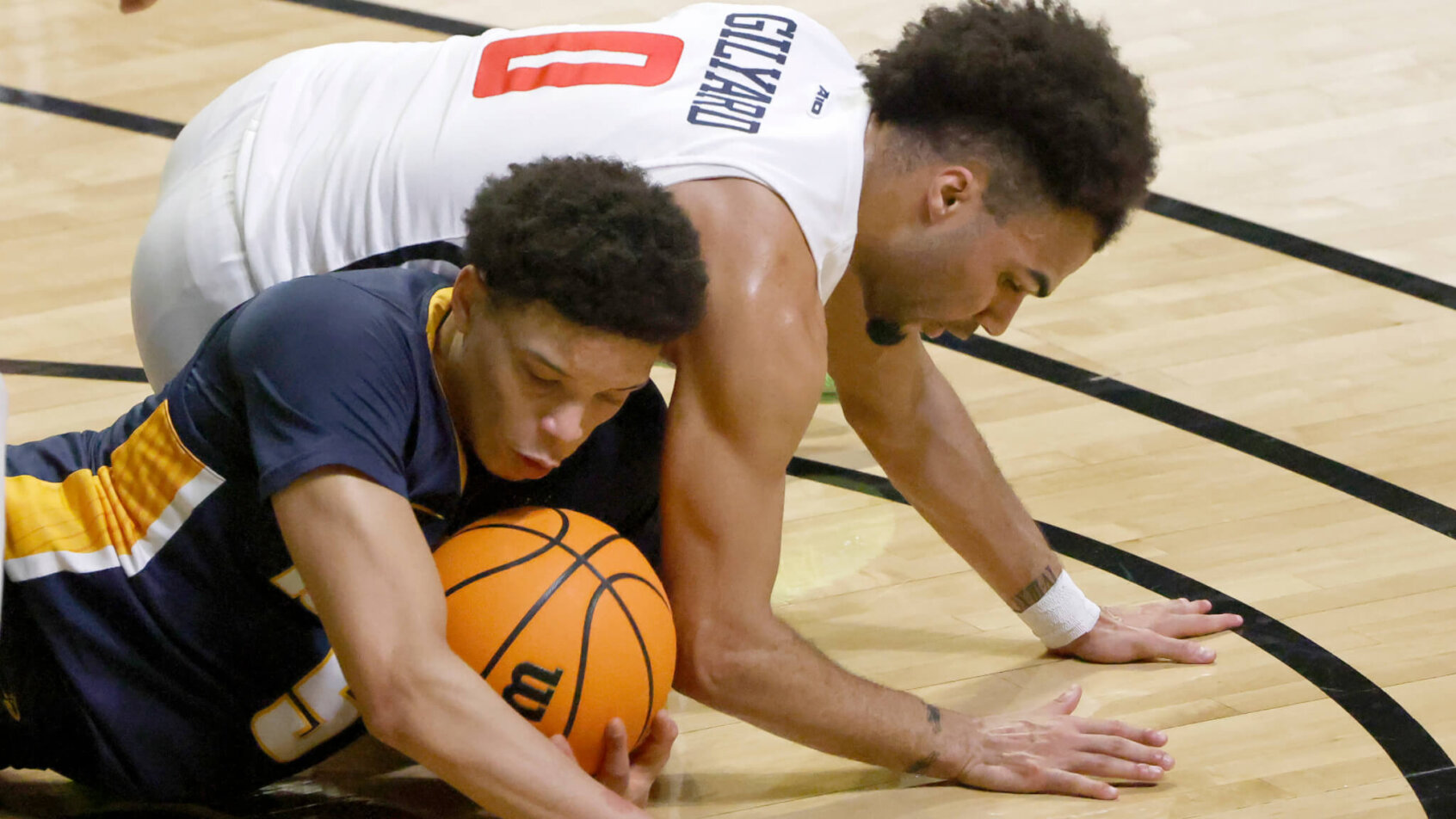 Toledo guard Ryan Rollins rolling on the ground after a loose ball