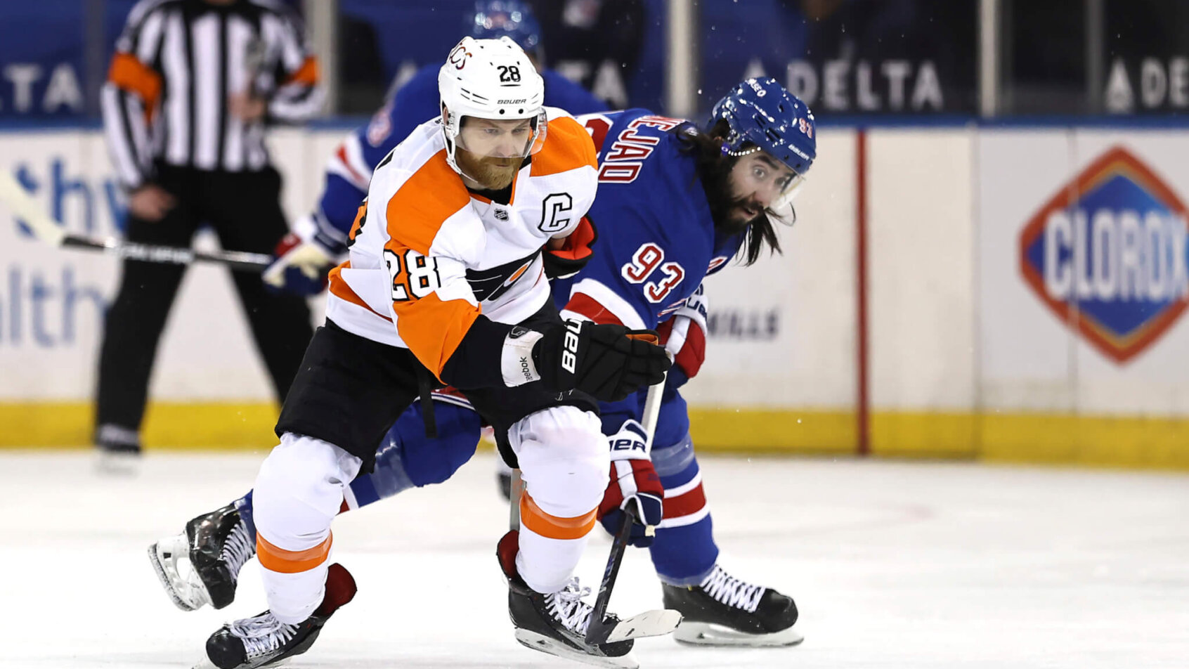 Philadelphia Flyers' Claude Giroux trying to keep the puck away from New York Rangers players during an NHL game.