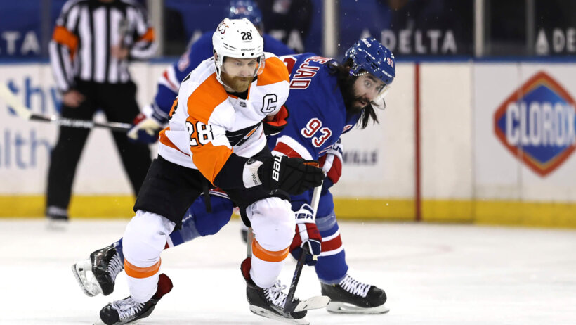 Philadelphia Flyers' Claude Giroux trying to keep the puck away from New York Rangers players during an NHL game.