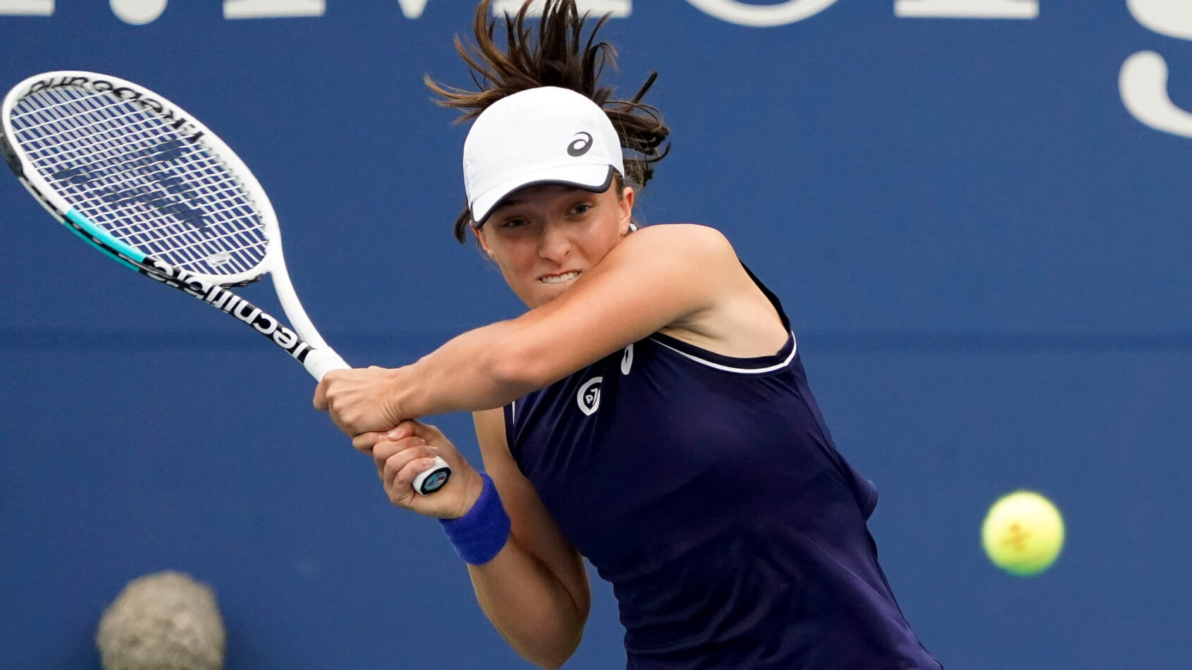 Iga Swiatek hitting a return shot during a tennis match.
