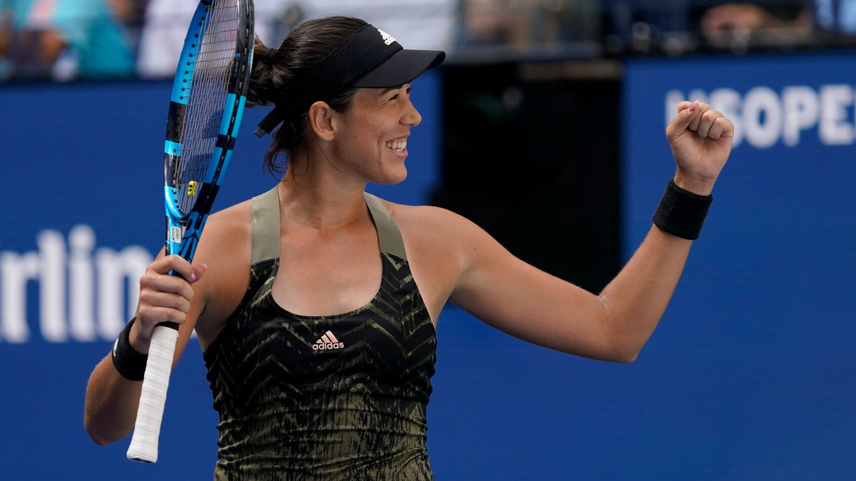 Garbine Muguruza reacting with a fist pump after defeating her opponent during a tennis match.
