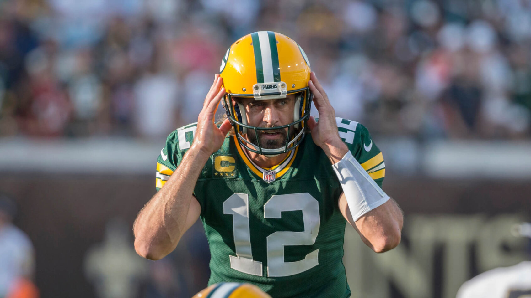 Aaron Rodgers holding hands to helmet while calling out play